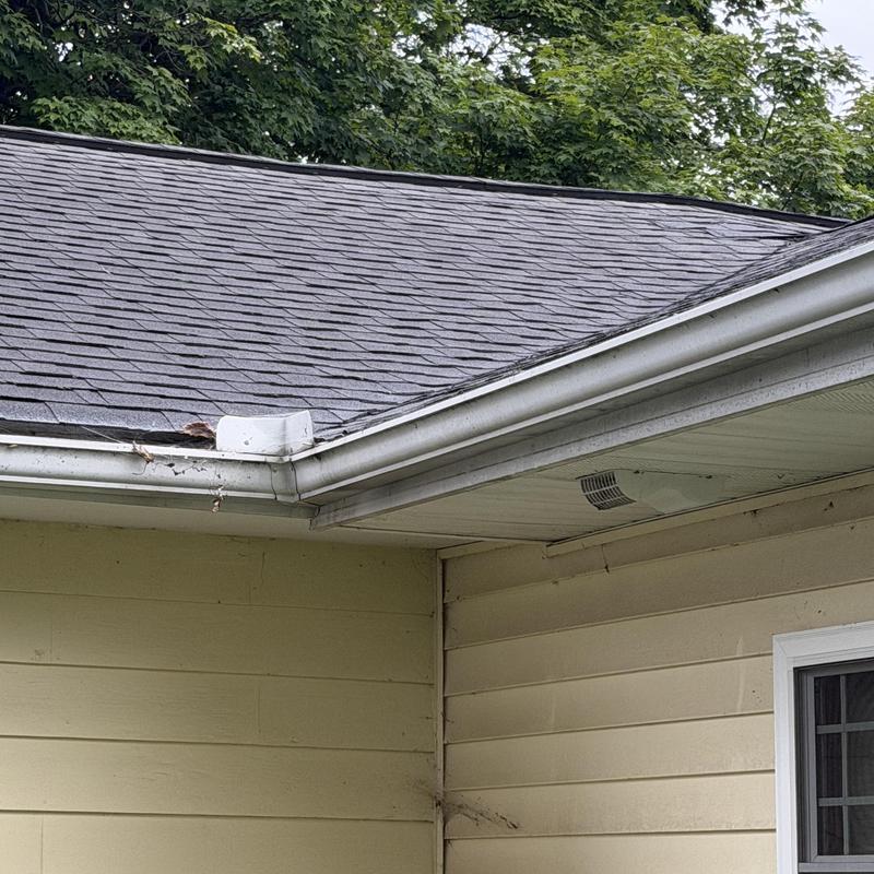 Asphalt shingle roof and gutter corner with damage