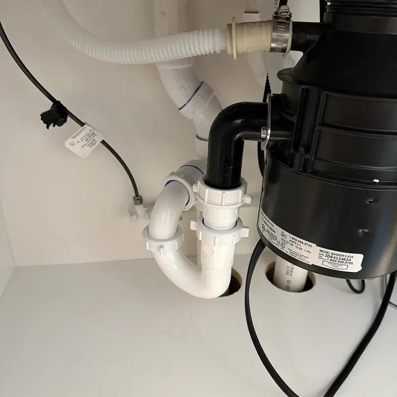 Garbage disposal plumbing with white PVC drain pipes