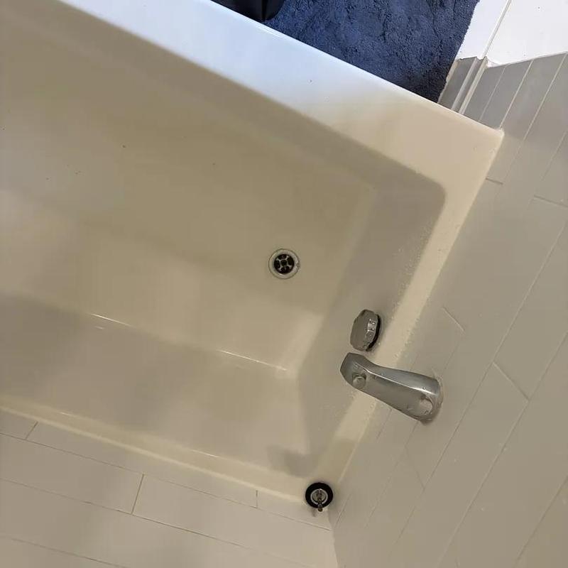 Bathtub with faucet and drain in bathroom corner