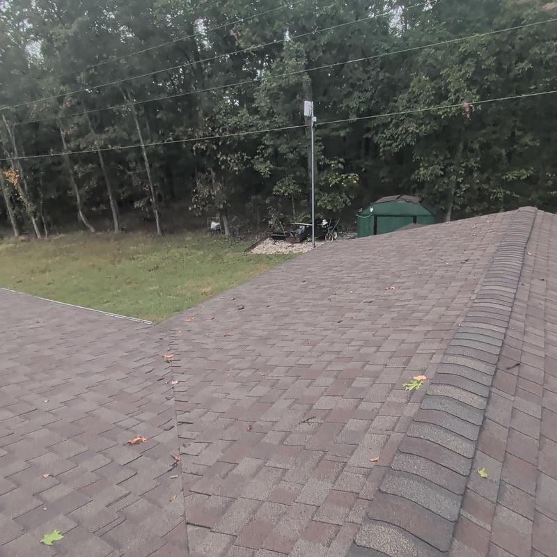 Asphalt shingle roof with ridge cap and tree backdrop