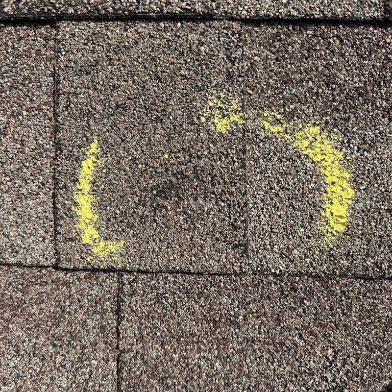 Asphalt shingle with hail damage marked in yellow