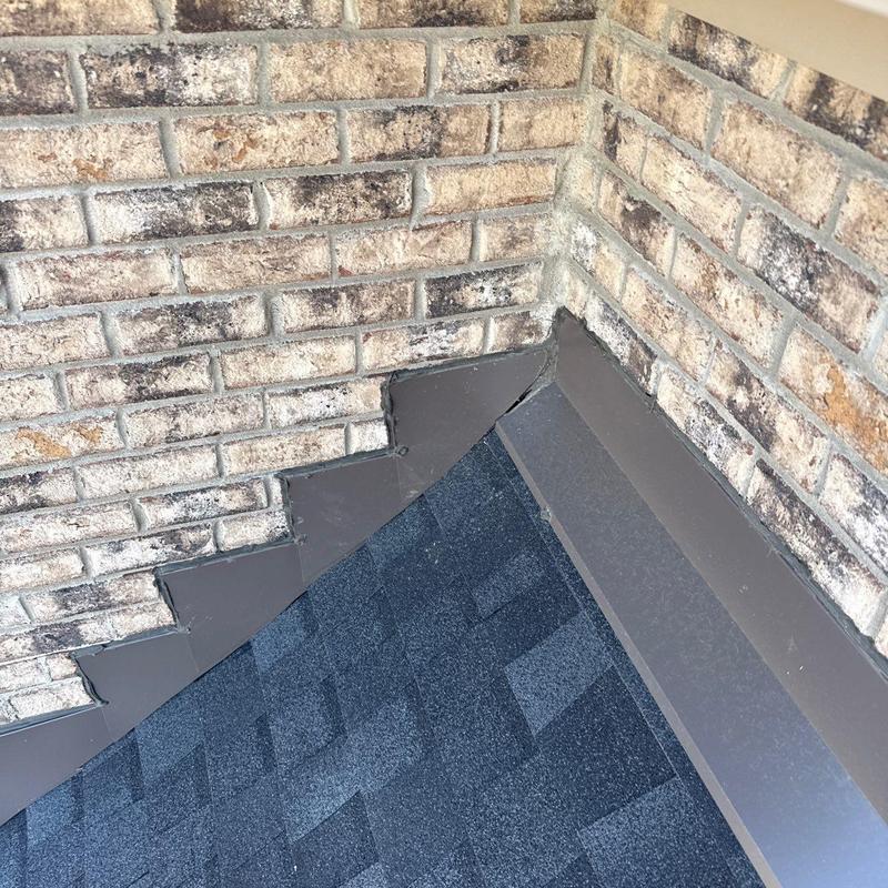 Roof flashing and shingle corner at brick wall