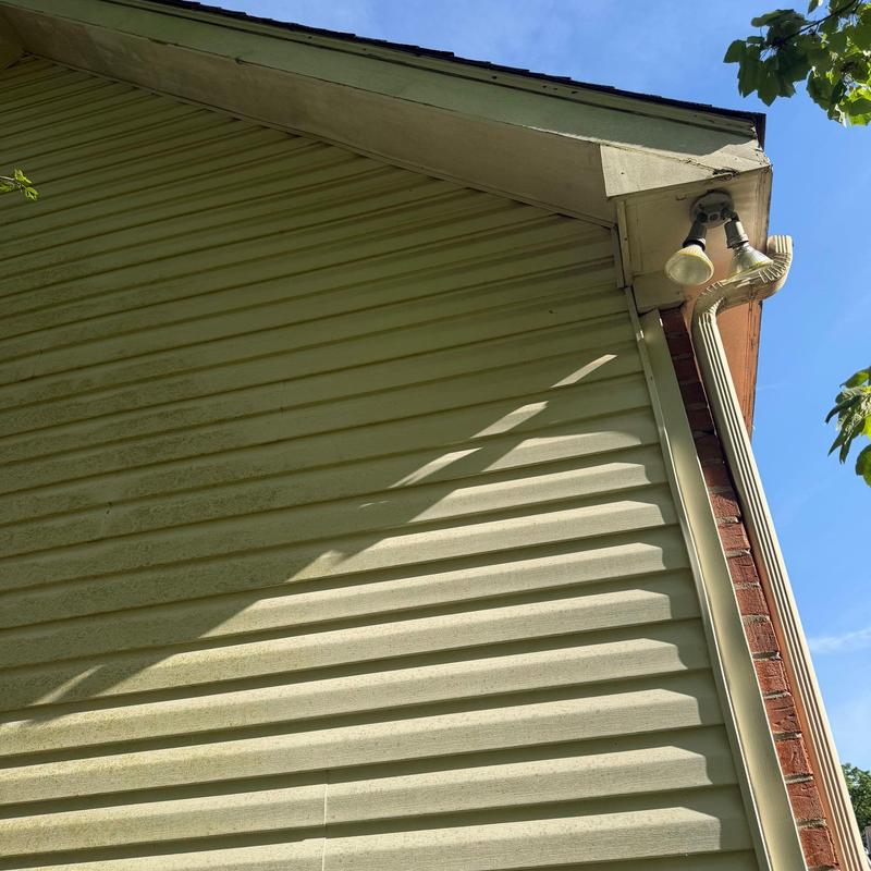 Vinyl siding with downspout and floodlight on home exterior
