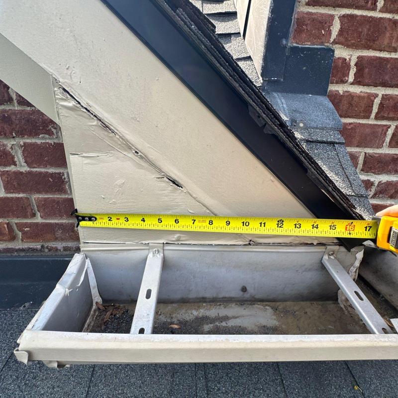 Roof gutter measuring hail damage near brick wall