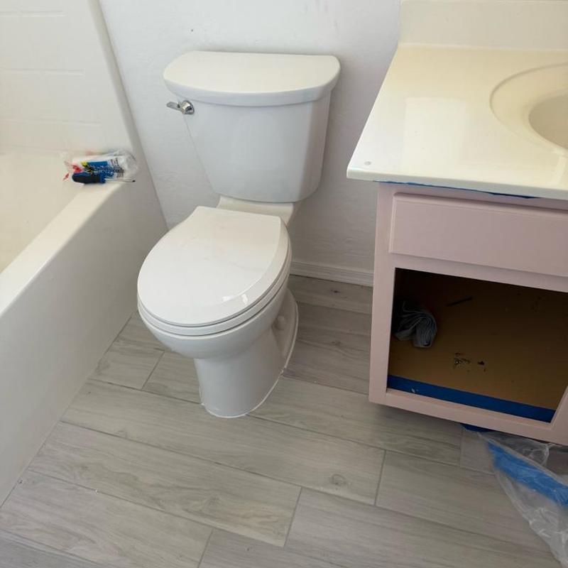 Toilet installation next to bathtub and empty vanity cabinet