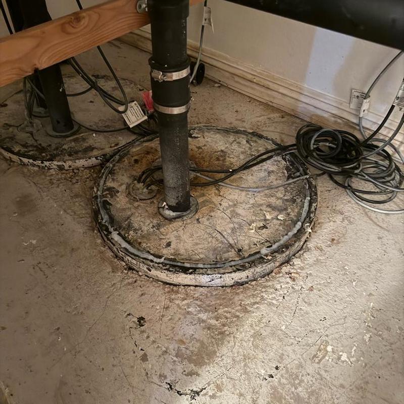 Sump pump basin with pipe and wiring in basement