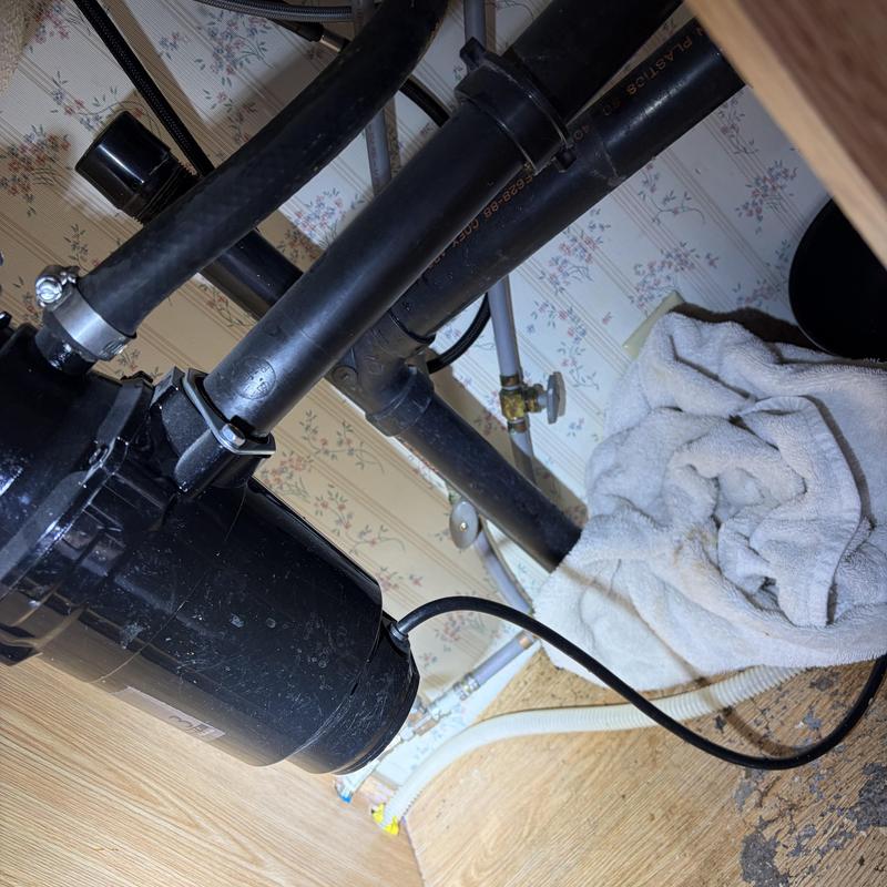 Garbage disposal with connected black drain pipes under sink