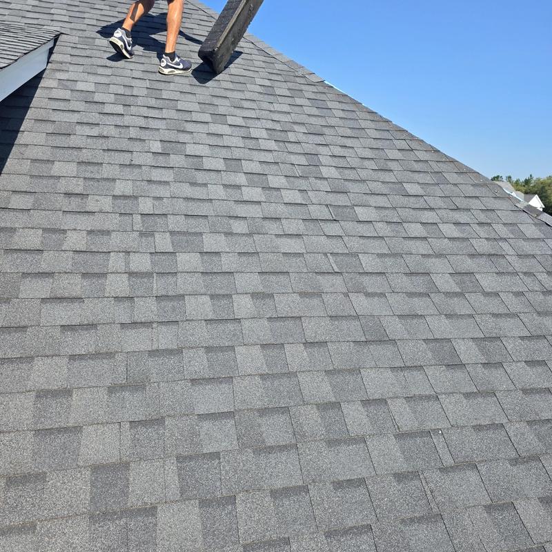 Asphalt shingle roof with worker removing old ridge shingles Asphalt shingle roof with worker removing old ridge shingles