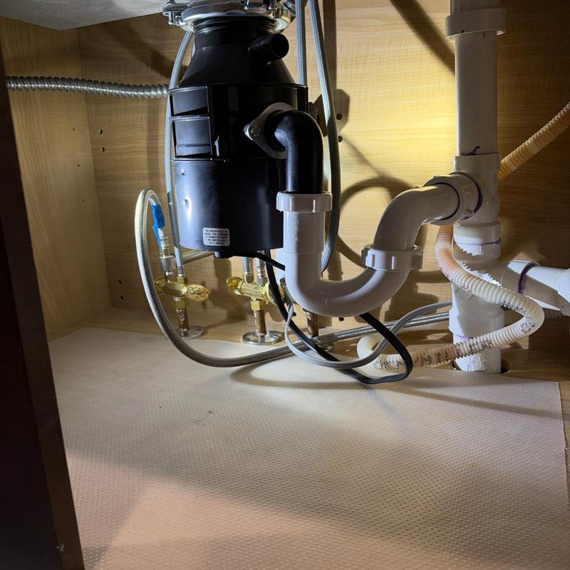 Garbage disposal and under-sink plumbing pipes in cabinet