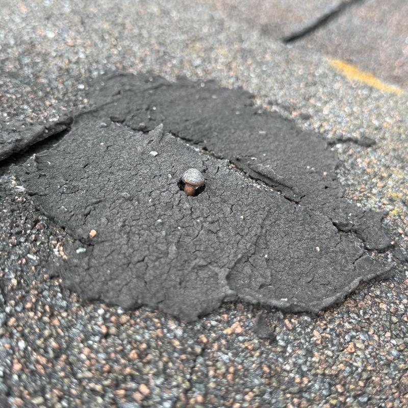 Rolled roofing with rusted exposed nail and patch Rolled roofing with rusted exposed nail and patch