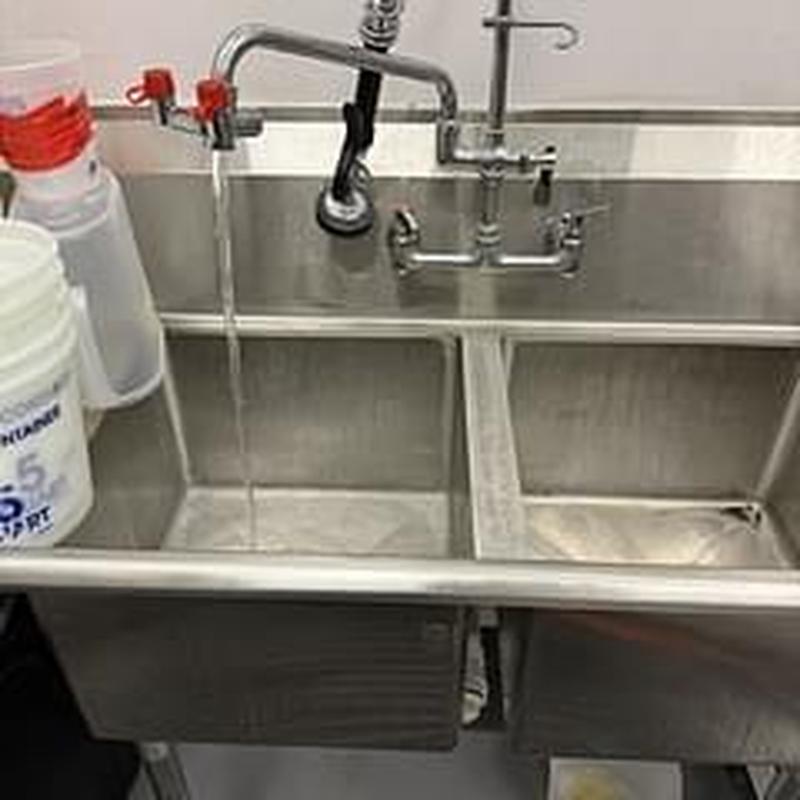 Basket strainer under commercial sink with faucet running