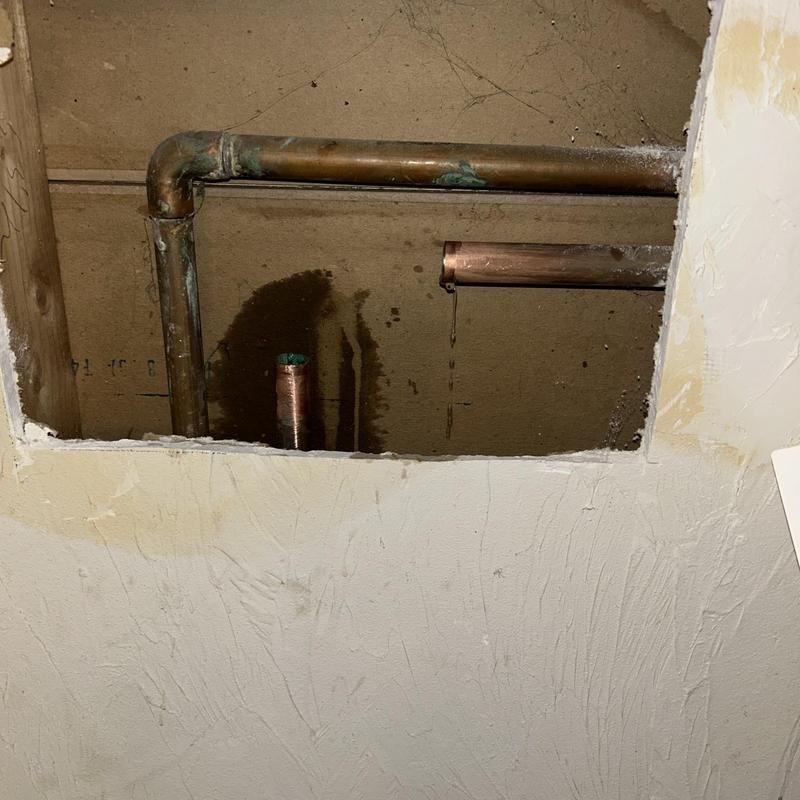 Copper water pipes inside drywall cutout with leak stains Copper water pipes inside drywall cutout with leak stains