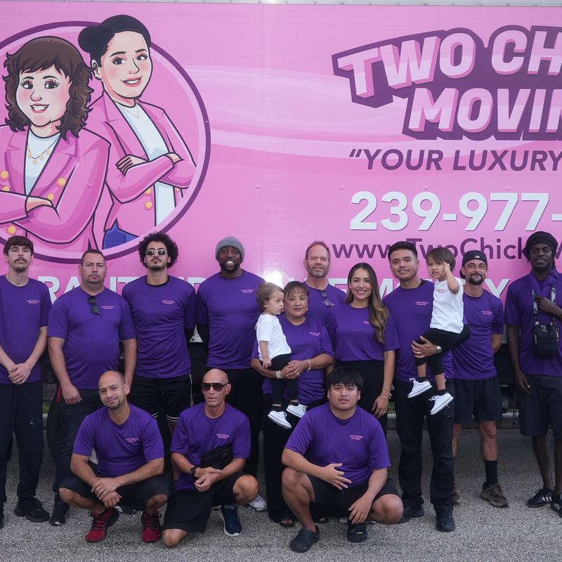 Moving truck team in purple shirts posing outdoors