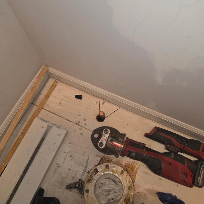 Copper water line capped with power tool on floor Copper water line capped with power tool on floor