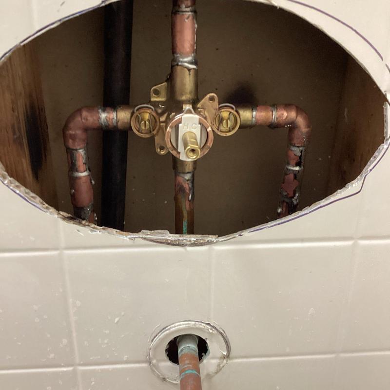 Shower valve and copper piping behind tile wall