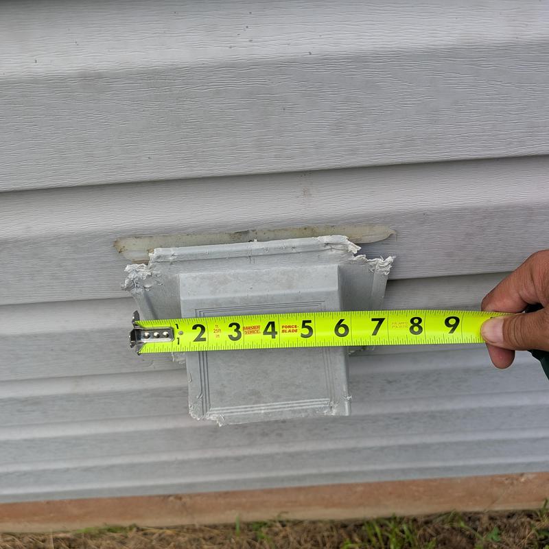 Damaged house siding with measuring tape extended