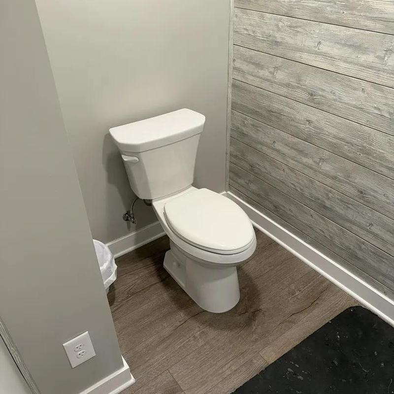 Toilet installation in new bathroom with wood accents