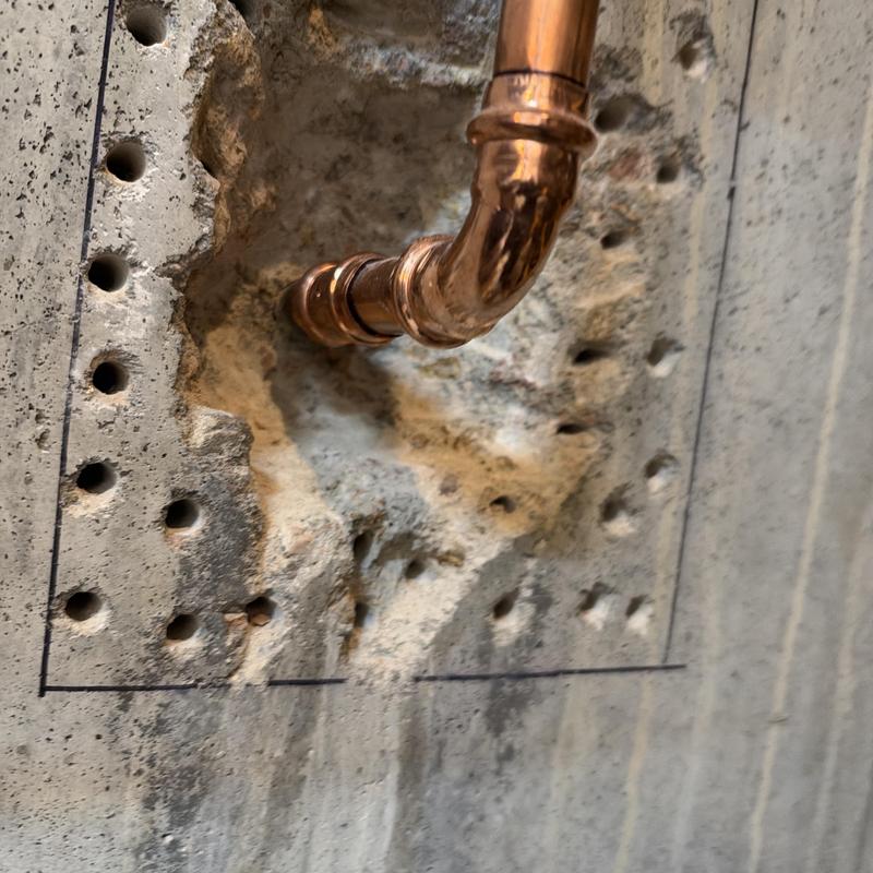 Copper piping installation through concrete wall with drilled holes