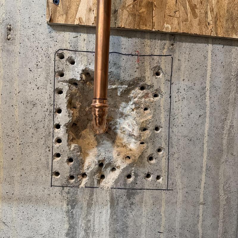 Copper piping installation through concrete wall with drilled holes