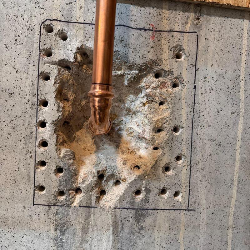 Copper piping installation through concrete wall with drilled holes