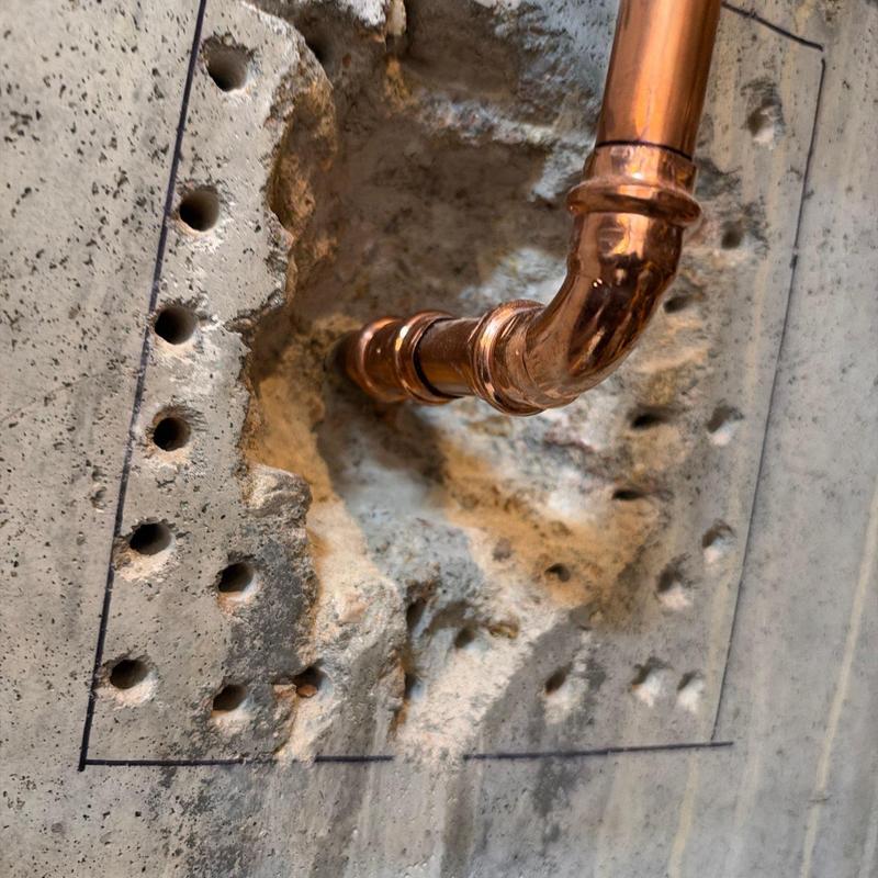 Copper piping through concrete wall with drilled holes