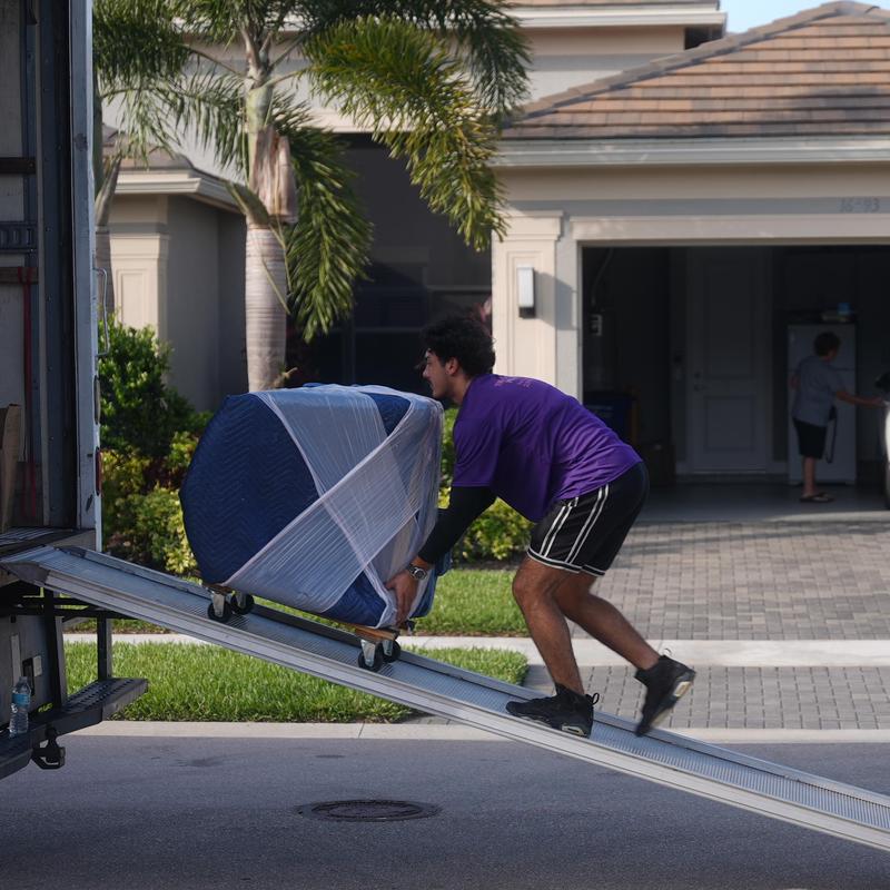 Moving dolly with wrapped furniture loading truck ramp