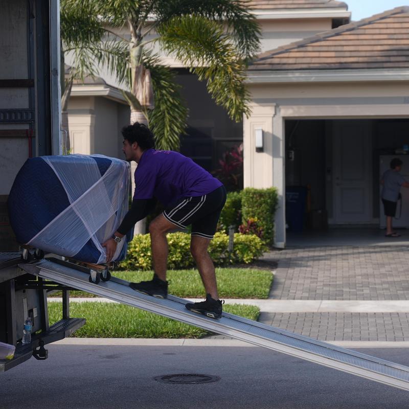 Upholstered chair loading onto moving truck ramp