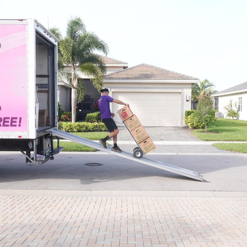 Moving boxes on dolly loading into truck ramp