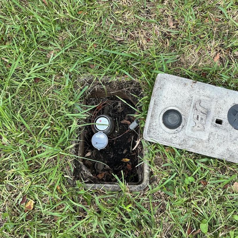 Water meter box with open lid in grass Water meter box with open lid in grass
