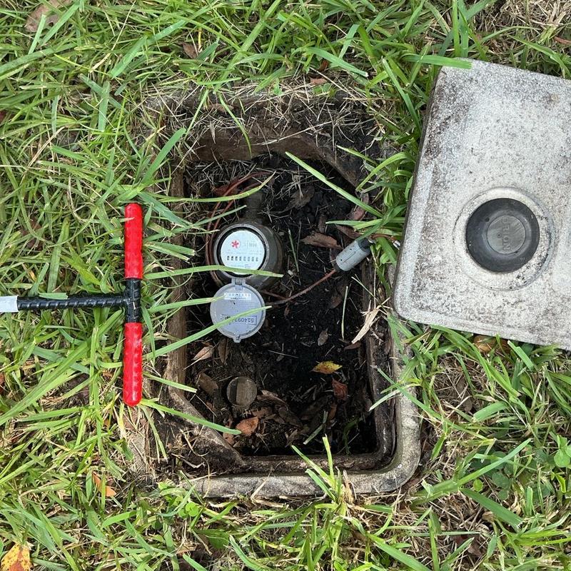 Water meter enclosure with valve repair site in grass Water meter enclosure with valve repair site in grass