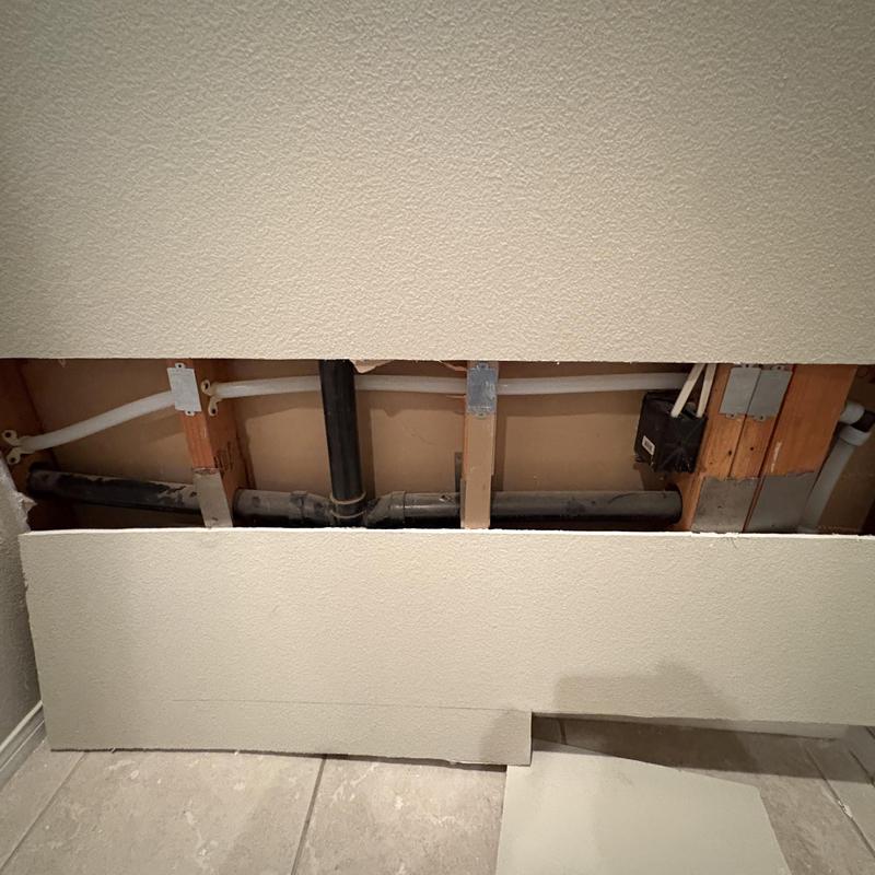 PEX-A water line and drain pipes behind drywall panel