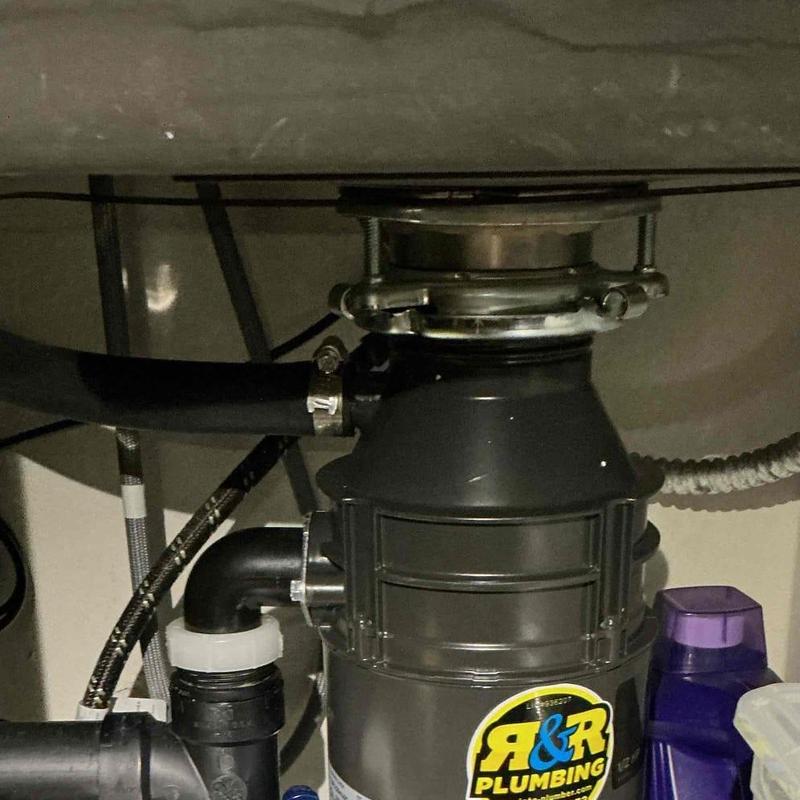 Garbage disposal unit installed under sink with plumbing