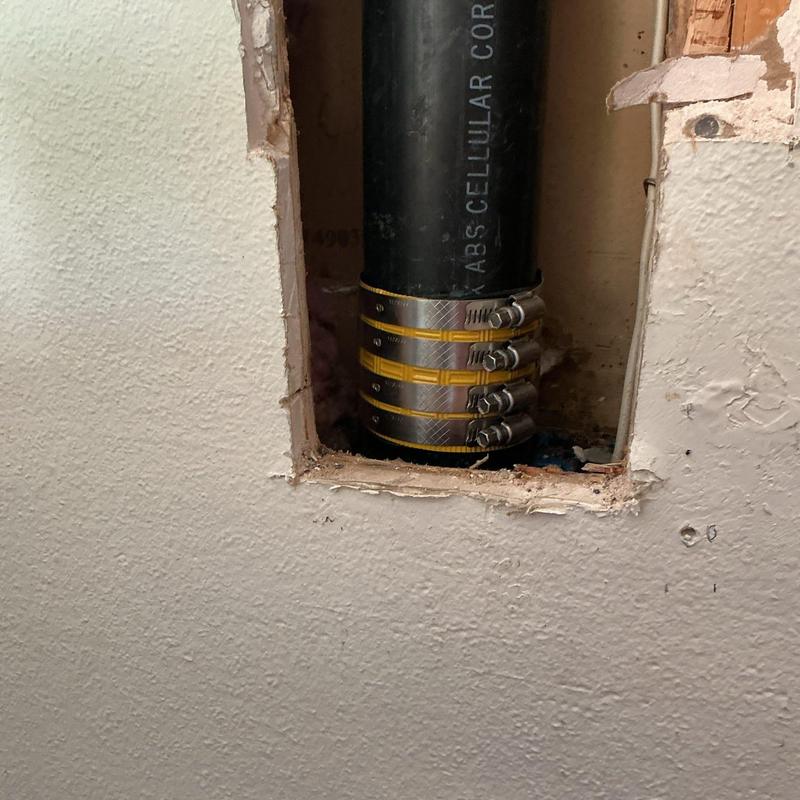 ABS drain pipe with metal clamps in wall cavity