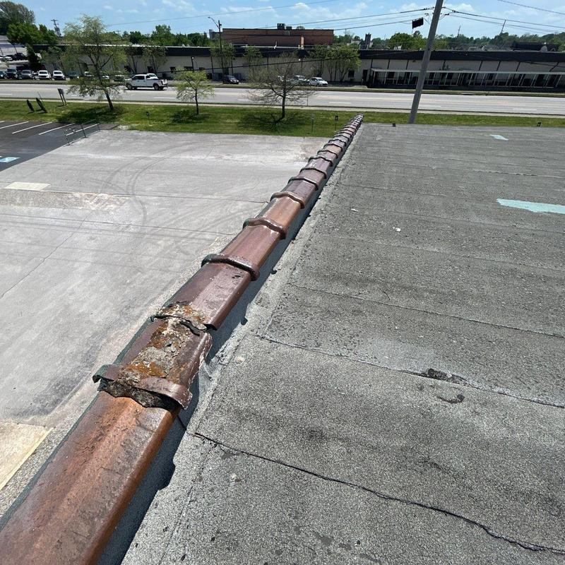 Metal roof ridge cap rust damage and wear on flat roof