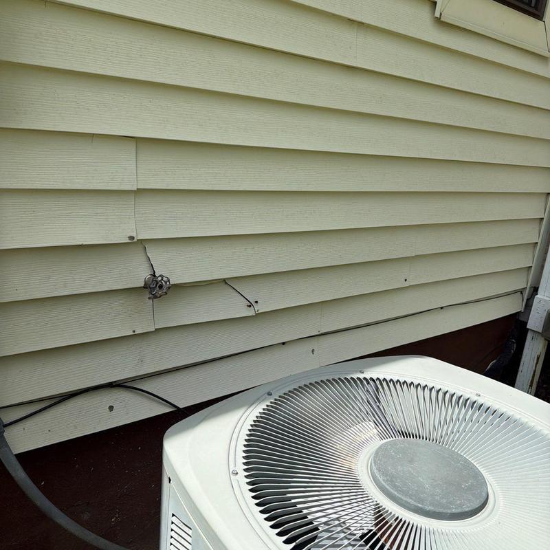 Vinyl siding with cracks near outdoor air conditioner unit