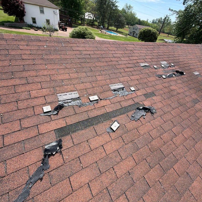 Roof shingles with hail and impact damage on roof ridge