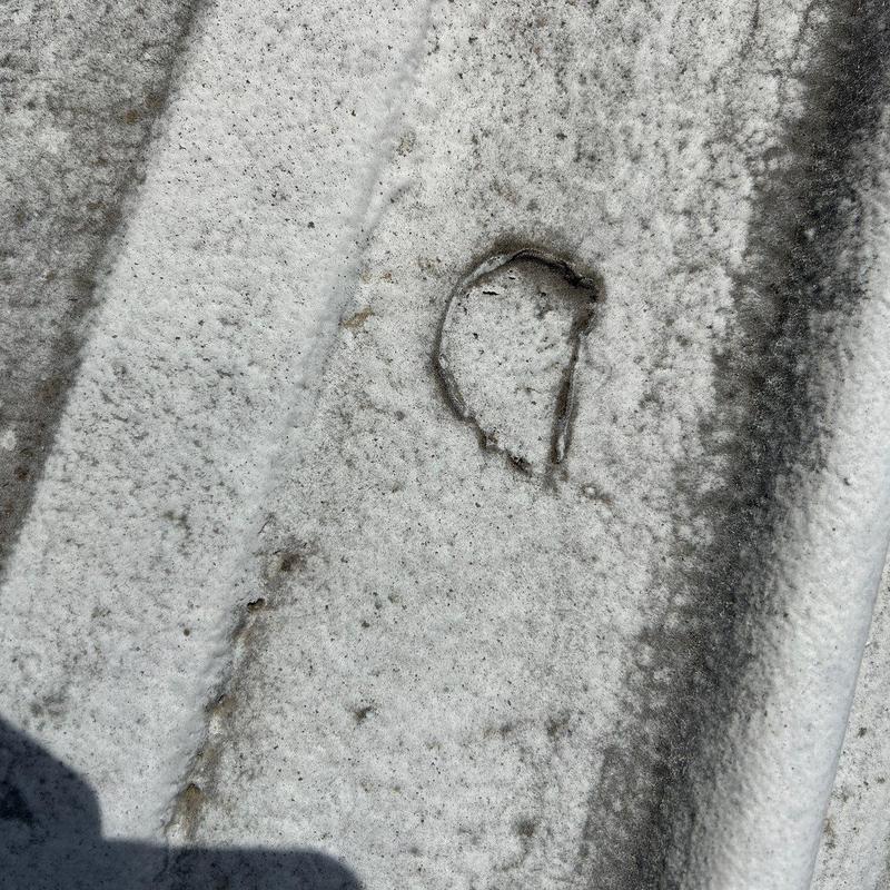 Metal roof panel hail damage close-up with dent and rust