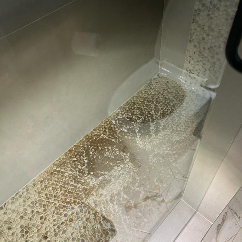 Shower floor with sewage backup stains in bathroom