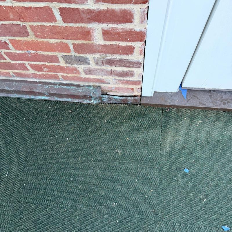 Metal flashing on brick wall base near door frame Metal flashing on brick wall base near door frame