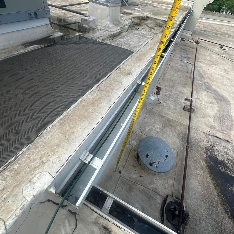 Roof gutter channel with measuring tape on commercial flat roof Roof gutter channel with measuring tape on commercial flat roof