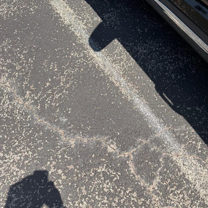 Asphalt parking lot surface with cracks and wear Asphalt parking lot surface with cracks and wear