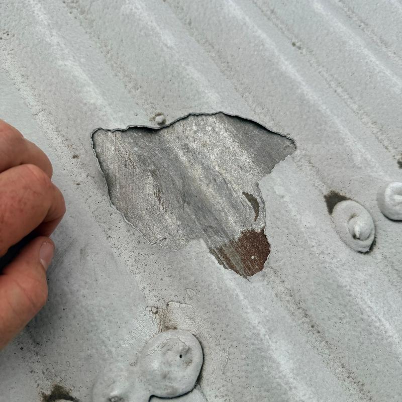 Metal roof panel with hail damage hole Metal roof panel with hail damage hole