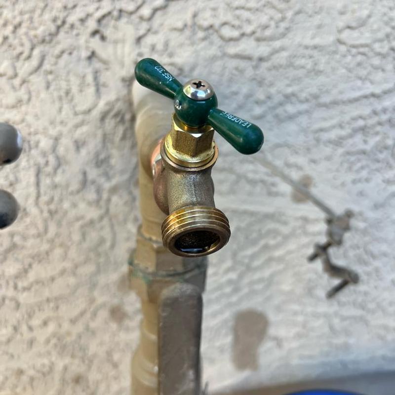 Brass multiturn hose bib valve with green handle installed