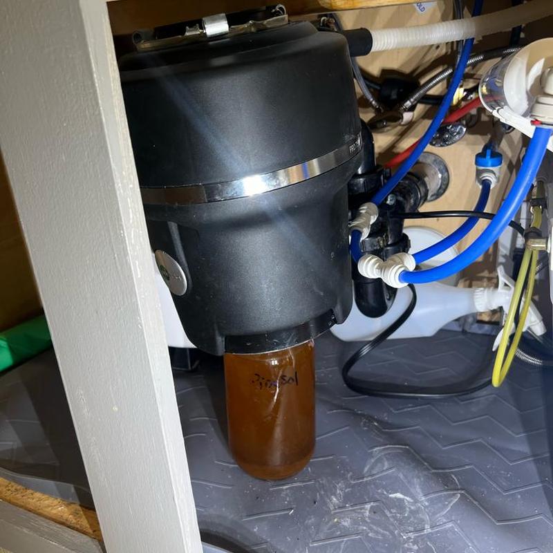 Garbage disposal unit under kitchen sink with plumbing