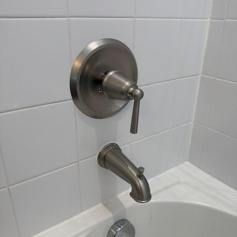 Tub spout with valve handle in white tile tub surround
