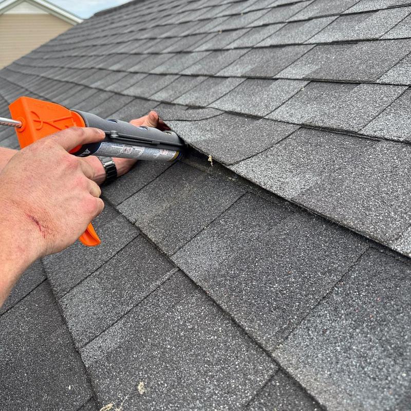 Roof shingles sealing with caulking gun on damaged area
