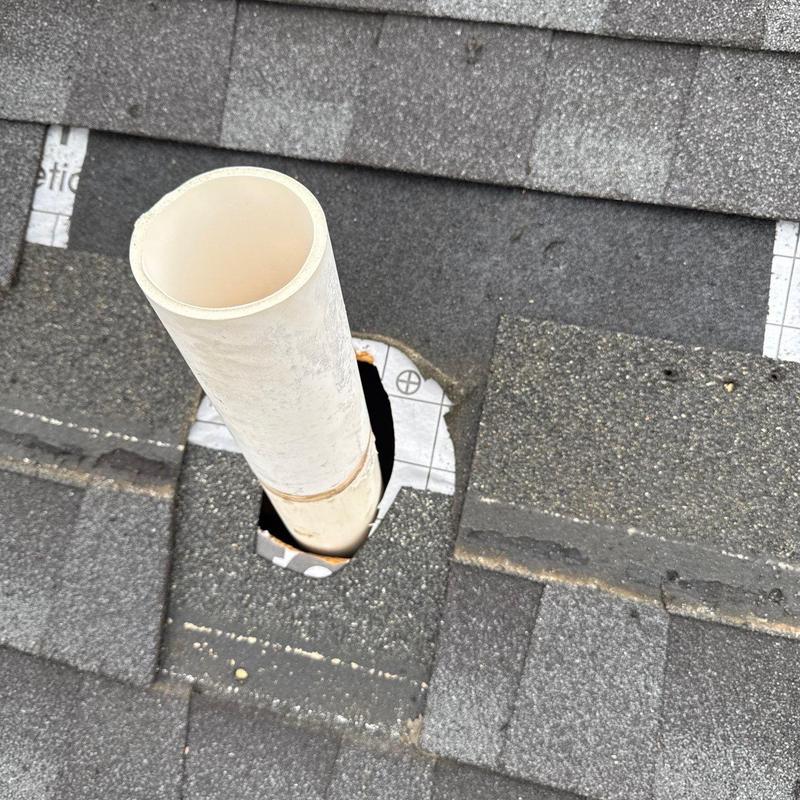 Roof pipe flashing with damaged shingles on asphalt roof