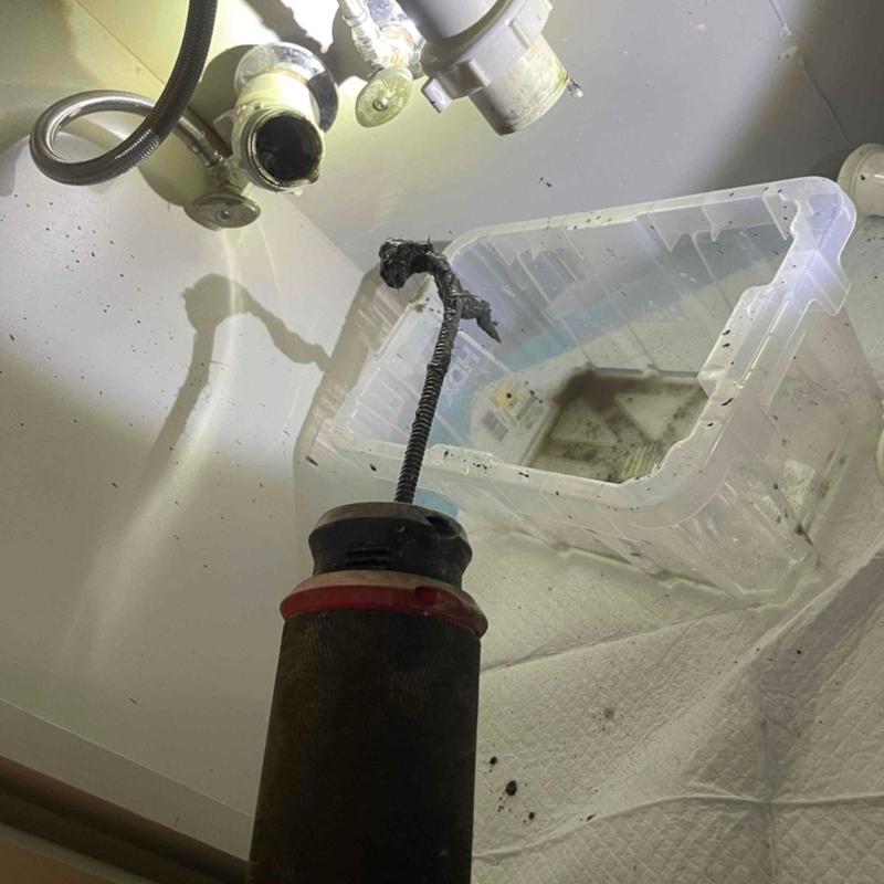 Bathroom sink drain cable clearing under cabinet