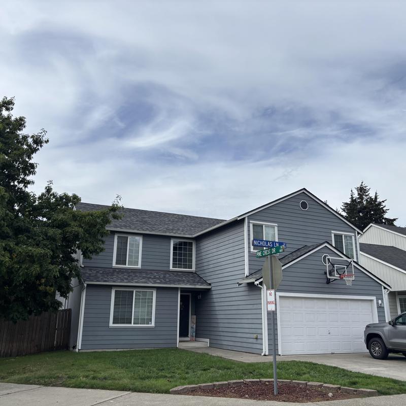 Asphalt shingle roof on gray two-story house