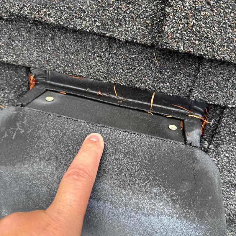 Roof flashing close-up with finger pointing at sealant